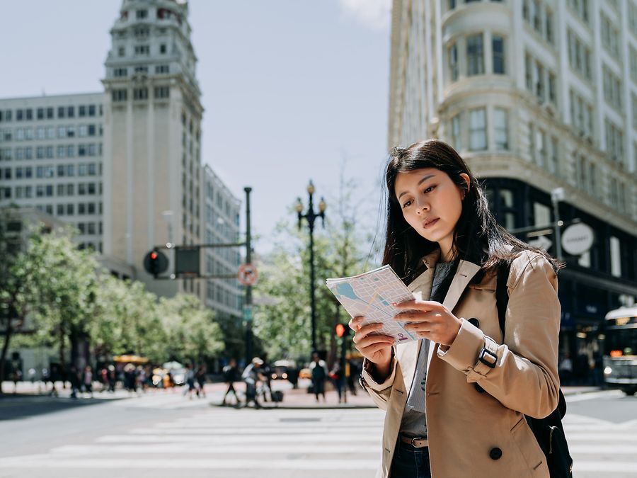 Standorte: Junge Asiatin, die auf eine Stadtkarte schaut